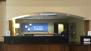 A reception desk with a Holiday Inn Express sign, a lamp, and framed pictures on the wall. - Holiday Inn Express Hotel & Suites Conover (Hickory Area) by IHG (Conover)