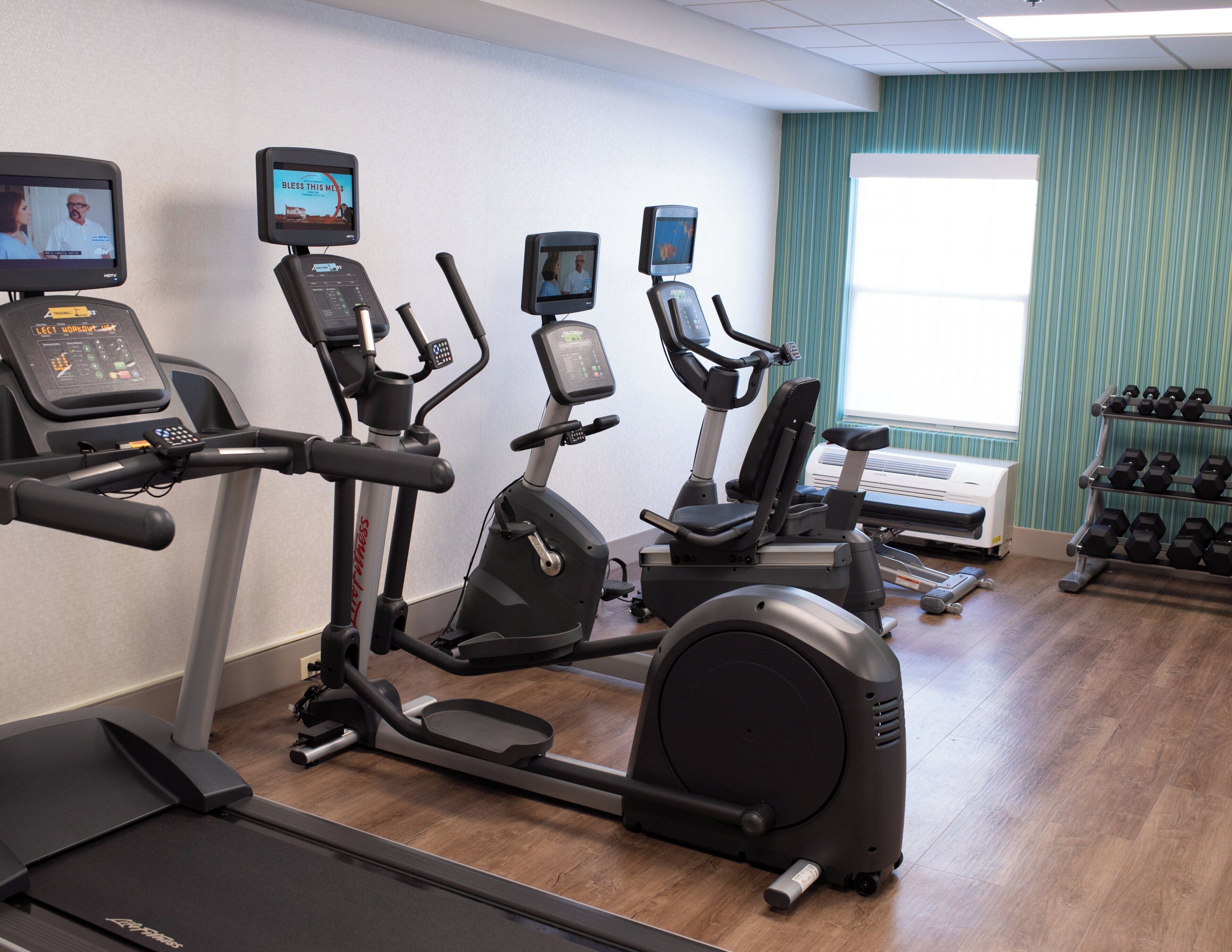 A gym with treadmills, elliptical machines, and a weight rack.