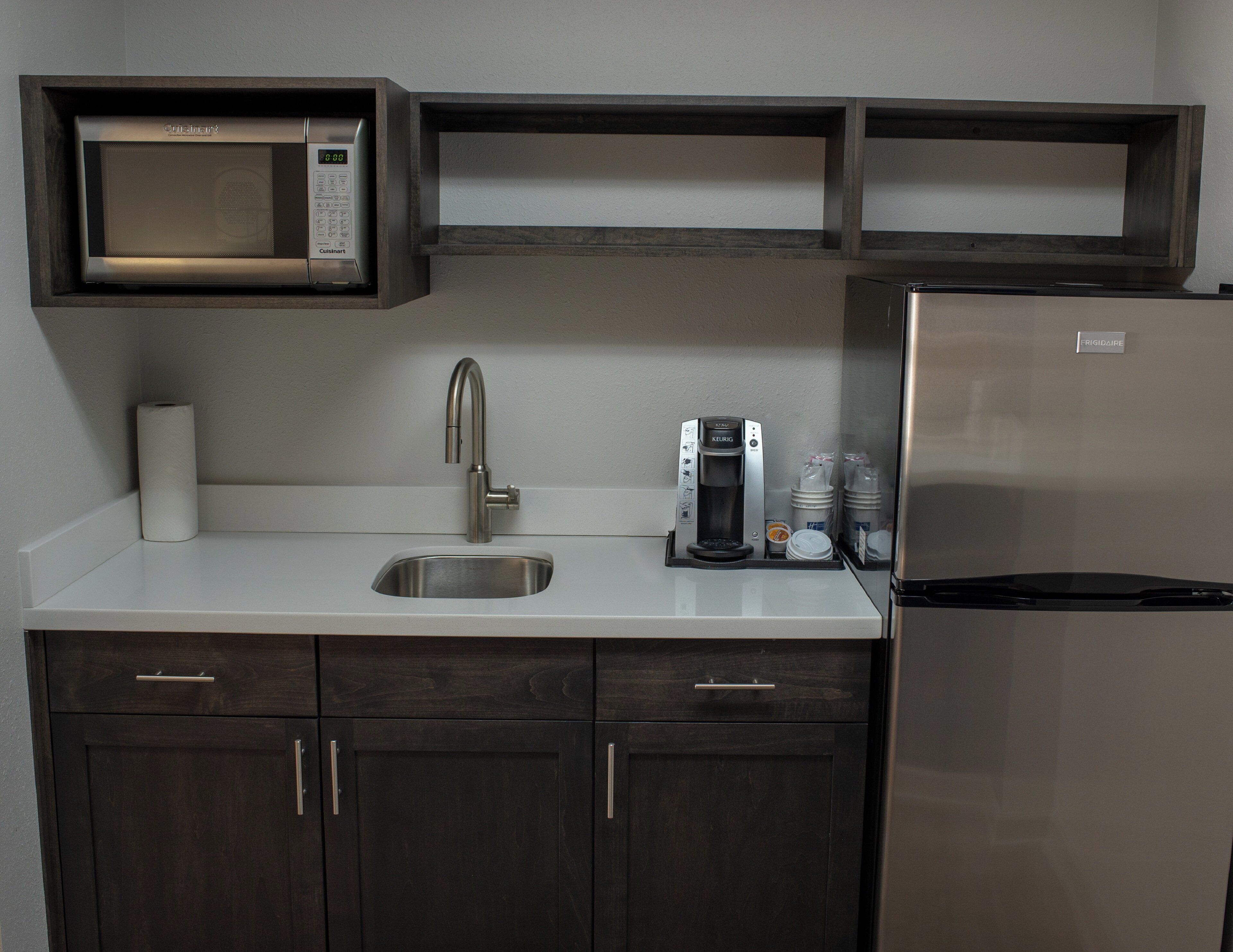 A kitchenette with a microwave, coffee maker, and refrigerator.