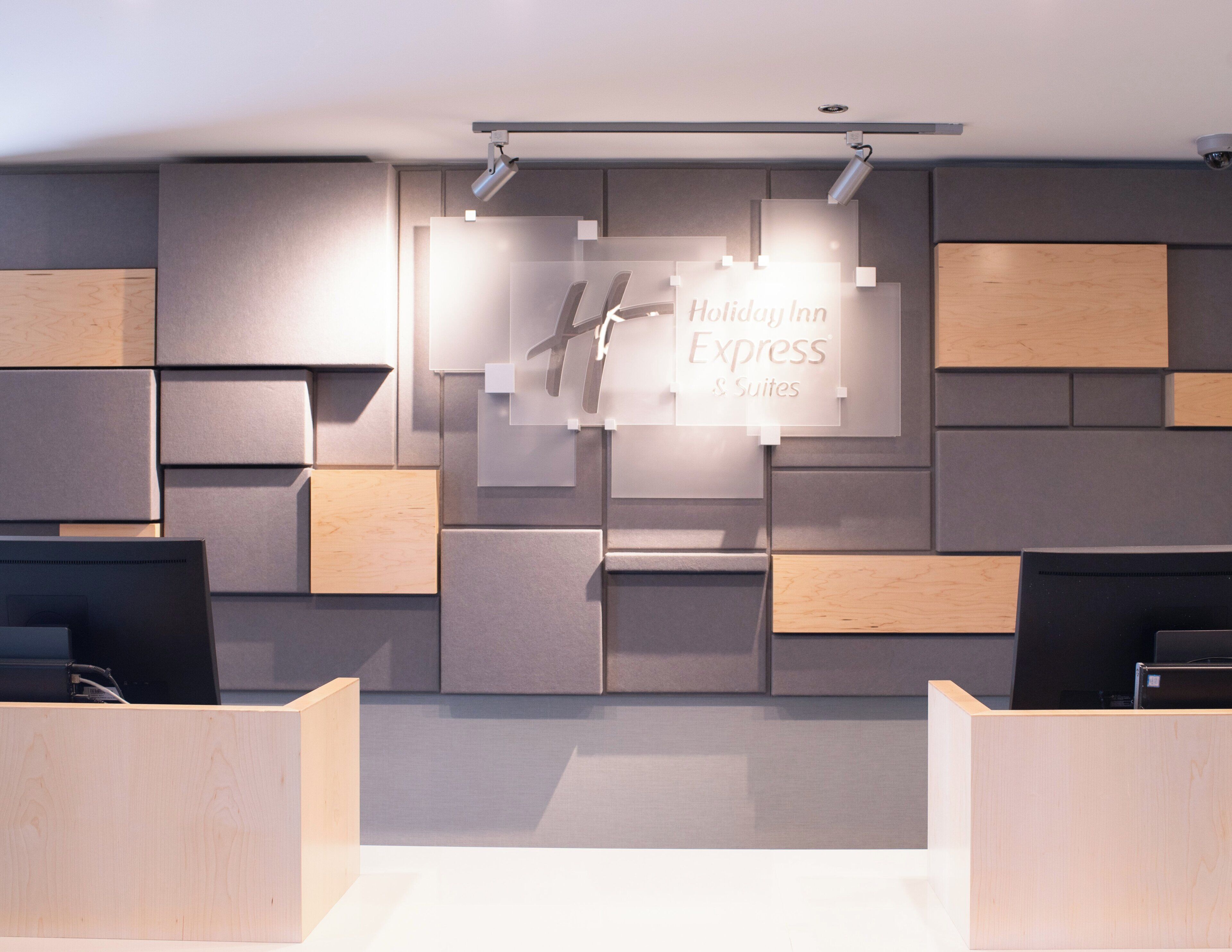 A modern hotel reception area with a central sign for Holiday Inn Express & Suites.