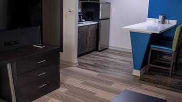 A compact kitchen with a refrigerator, microwave, and coffee maker. There is a small dining area with a table and a chair.