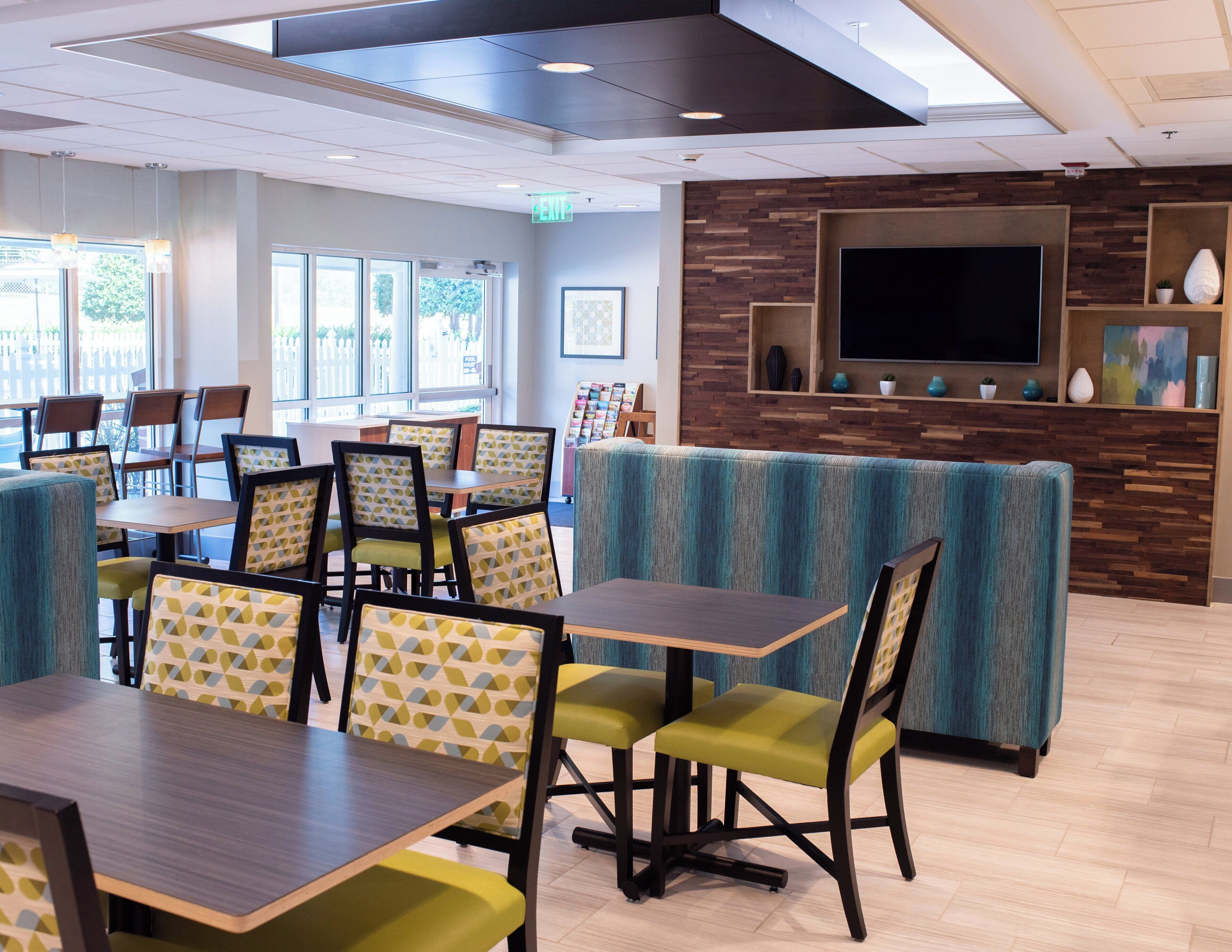 Un restaurant moderne avec des banquettes et des tables, un téléviseur à écran plat et un mur décoratif en bois.