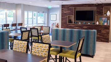 A modern restaurant interior with booths and tables, a flat-screen TV, and a wooden accent wall.