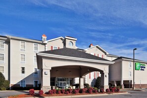 Un hotel con vestíbulo cubierto, varias ventanas y el letrero de Holiday Inn Express.
