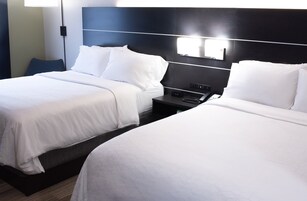 Habitación de hotel con dos camas, una mesita de noche y una lámpara fijada a la pared.
