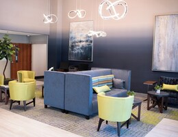 A modern lounge area with seating, a coffee table, and a large abstract painting on the wall.