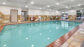 Una piscina con borde de azulejos, vestuario y puerta.