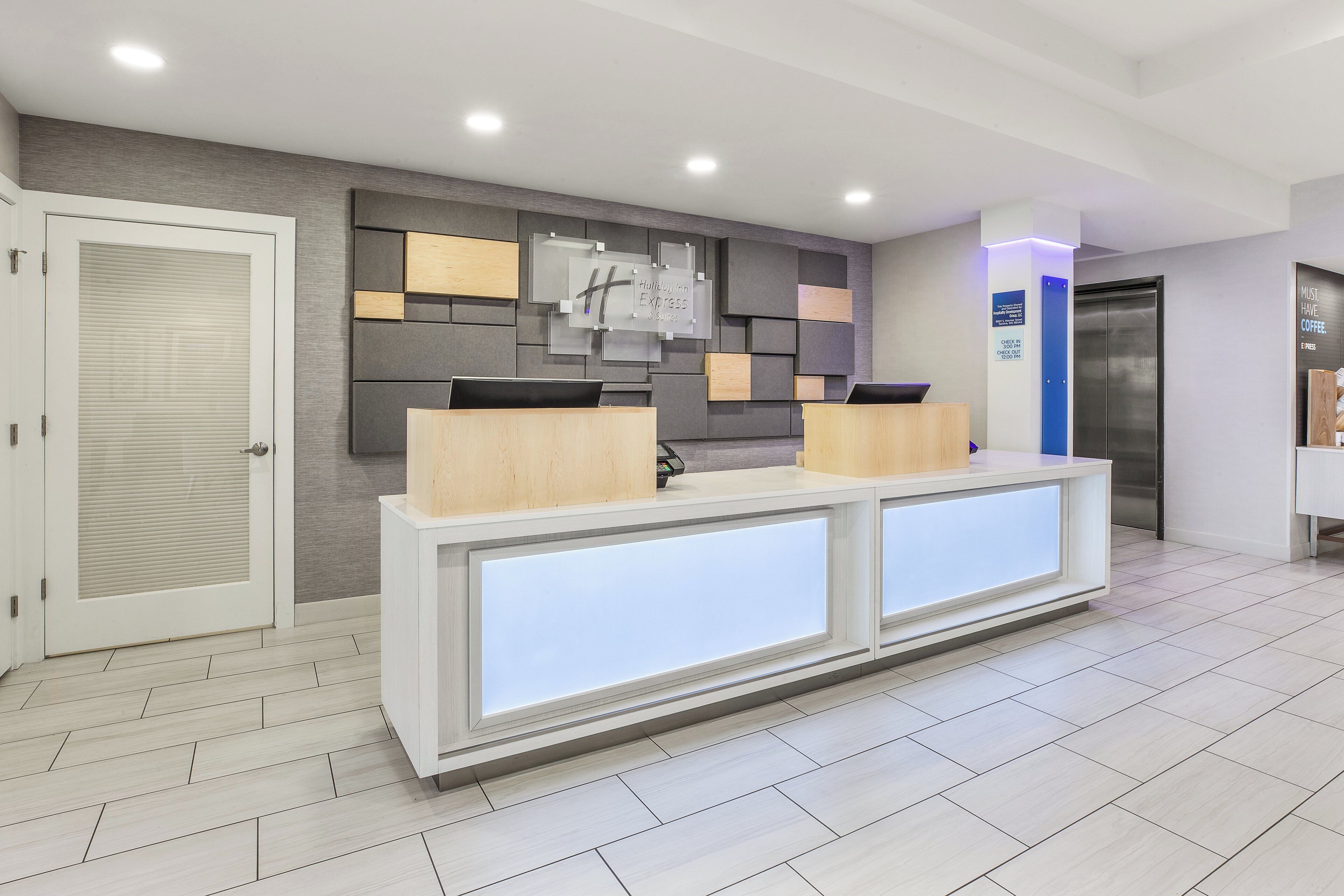 A reception desk with a modern design, a closed door to the left, and a wall-mounted sign above it.