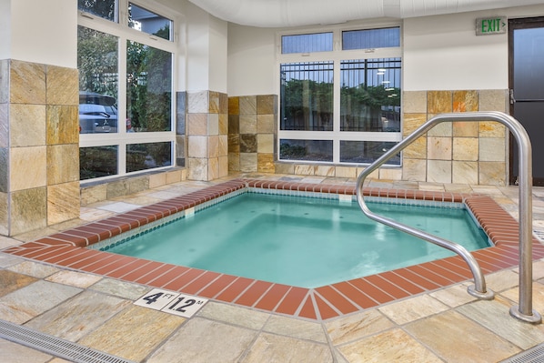 A rectangular indoor pool with a 4'12" depth marker, surrounded by stone tiles and large windows. - Holiday Inn Express & Suites Tacoma by IHG (Tacoma)