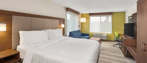 A hotel room with a large bed, a desk, a chair, and a television.