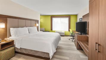 A hotel room with a large bed, a television, a desk with a chair, and a wardrobe.