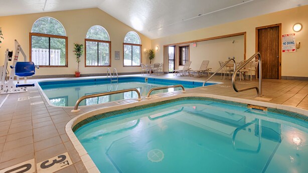 Una amplia piscina interior con carriles delimitados, una silla de socorrista y un cartel con las normas de la piscina.