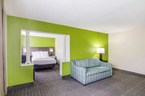 A hotel room with a bed, a sofa, a nightstand, and a lamp. - Quality Inn near University of Mobile (Saraland)