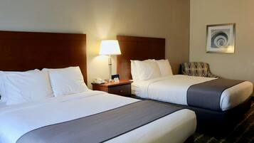 Une chambre d’hôtel avec deux lits, une table de chevet avec une lampe, un téléphone et une œuvre d’art abstraque encadrée au mur.