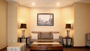 A hotel room with a sofa, two lamps, a framed picture on the wall, and a small table. - Best Western Fostoria Inn & Suites (Fostoria)
