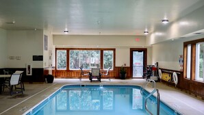 A pool area with a 'NO DIVING' sign, a table with chairs, and a view of trees through large windows. - Best Western Fostoria Inn & Suites (Fostoria)
