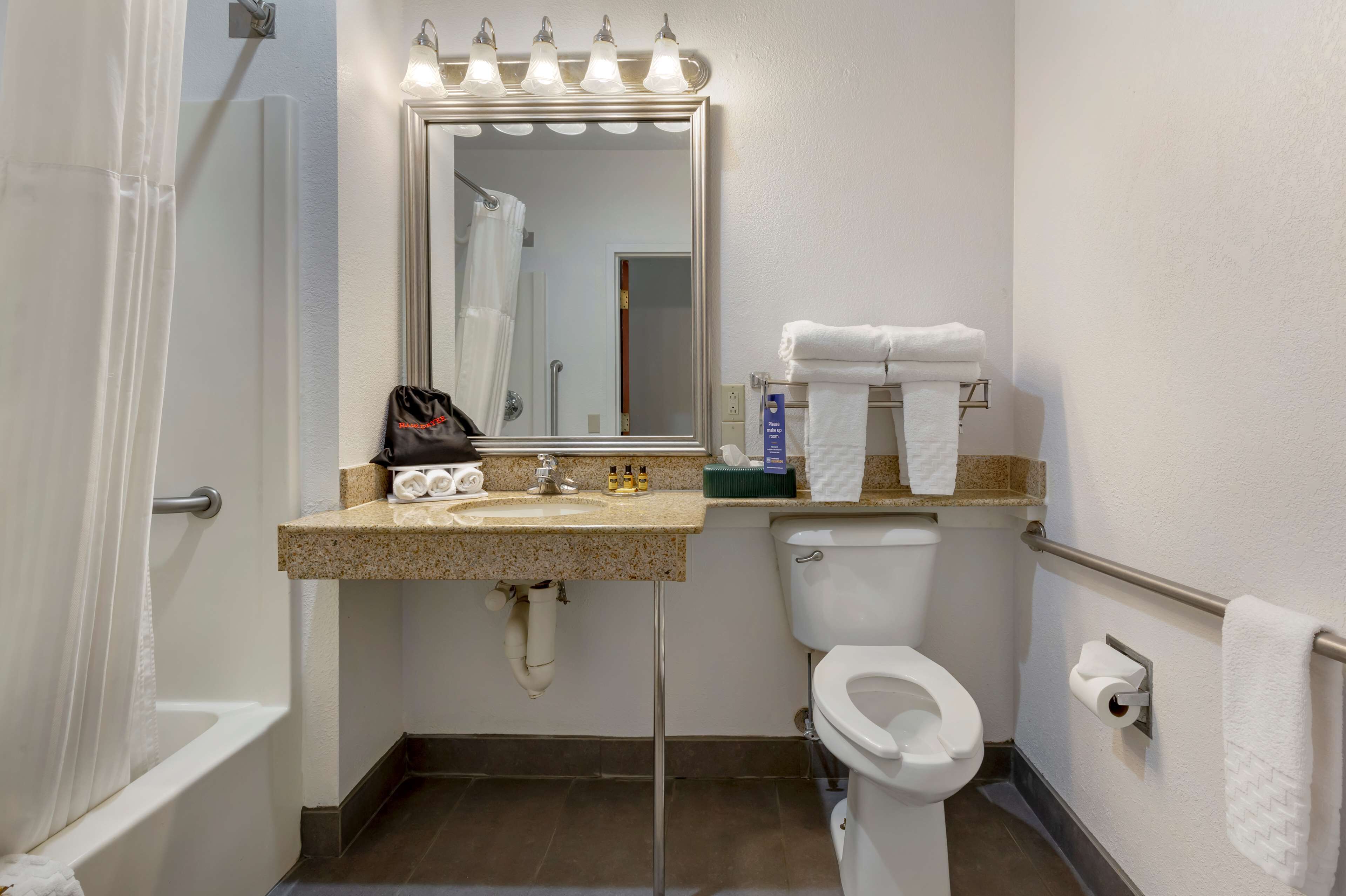 A bathroom with a sink, mirror, vanity, toilet, and towel rack.