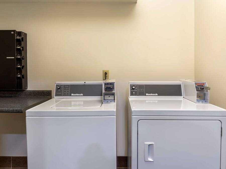 Two white Huebsch brand front-loading washing machines in a laundry room with a black cabinet above.