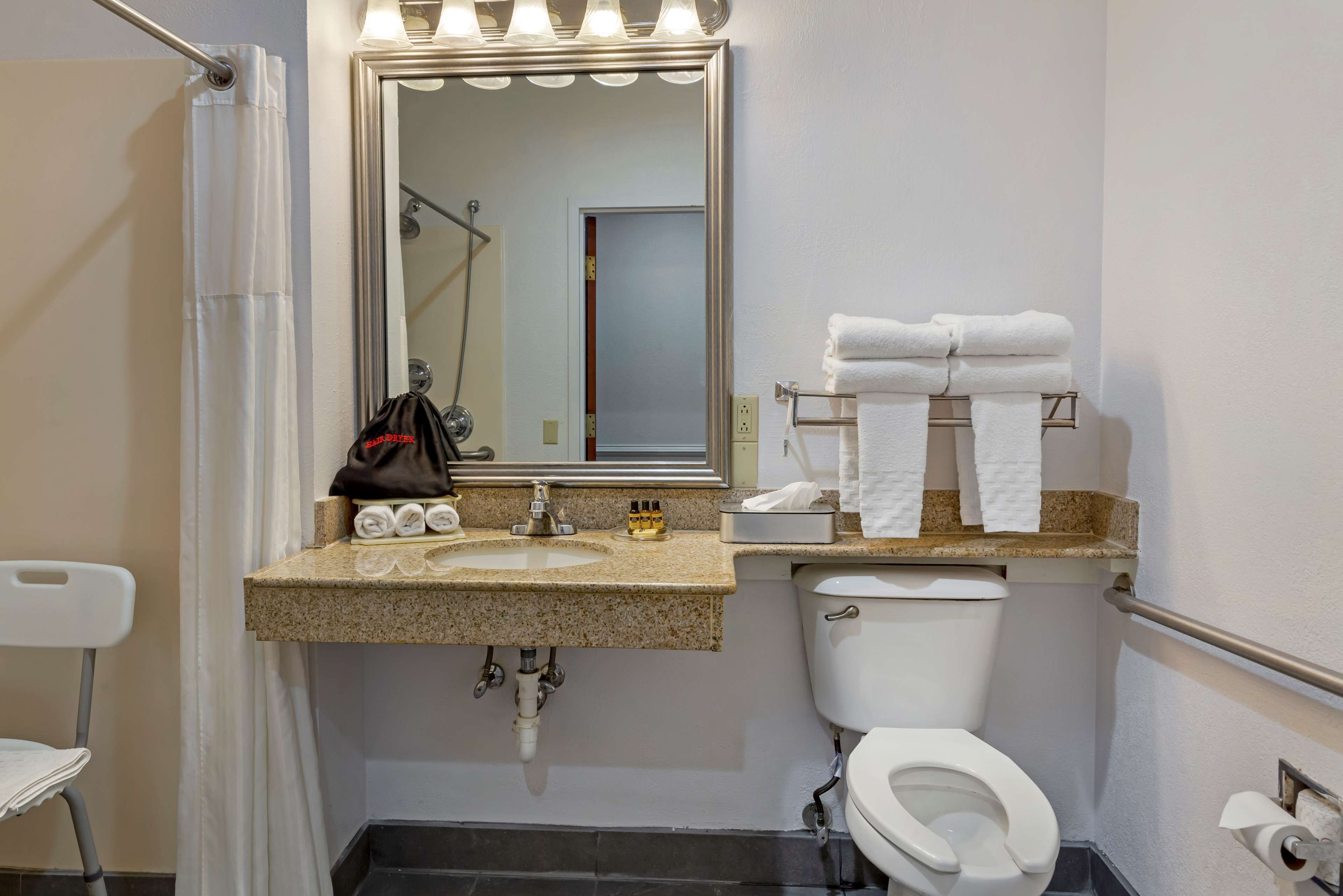 A bathroom with a sink, mirror, towel rack, toilet, and shower curtain.