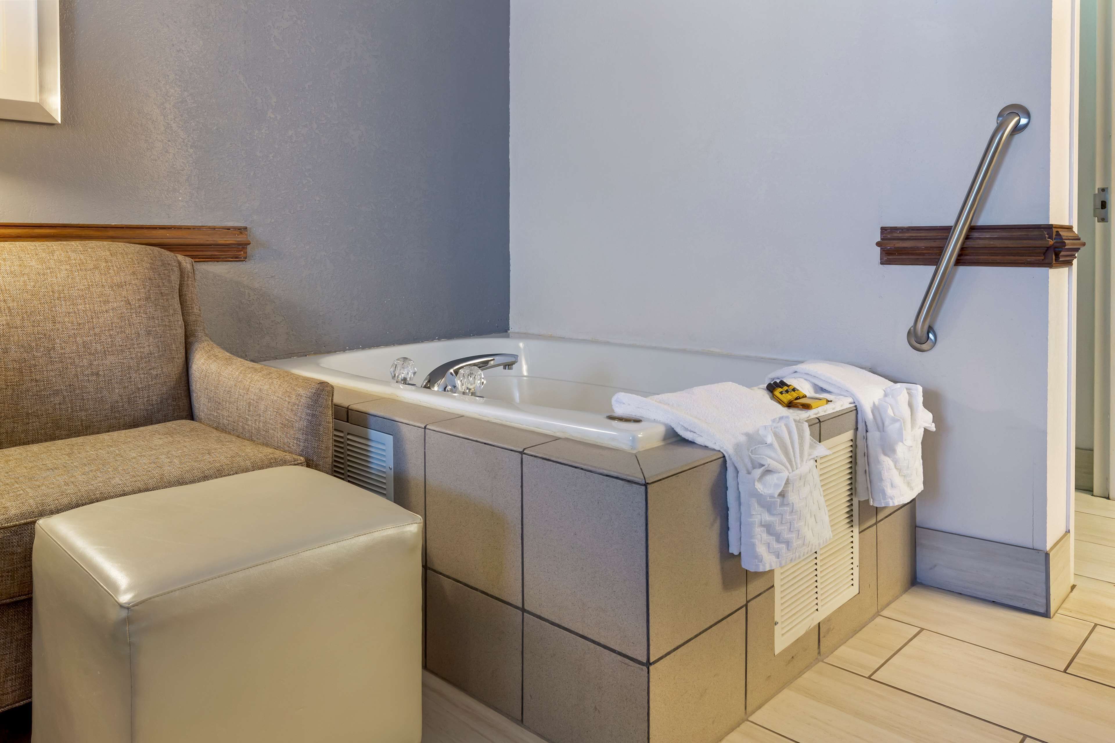 Un bagno con una vasca, un portasciugamani e una barra di sostegno.