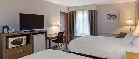 A hotel room with two beds, a desk with a microwave, a TV, and a chair.