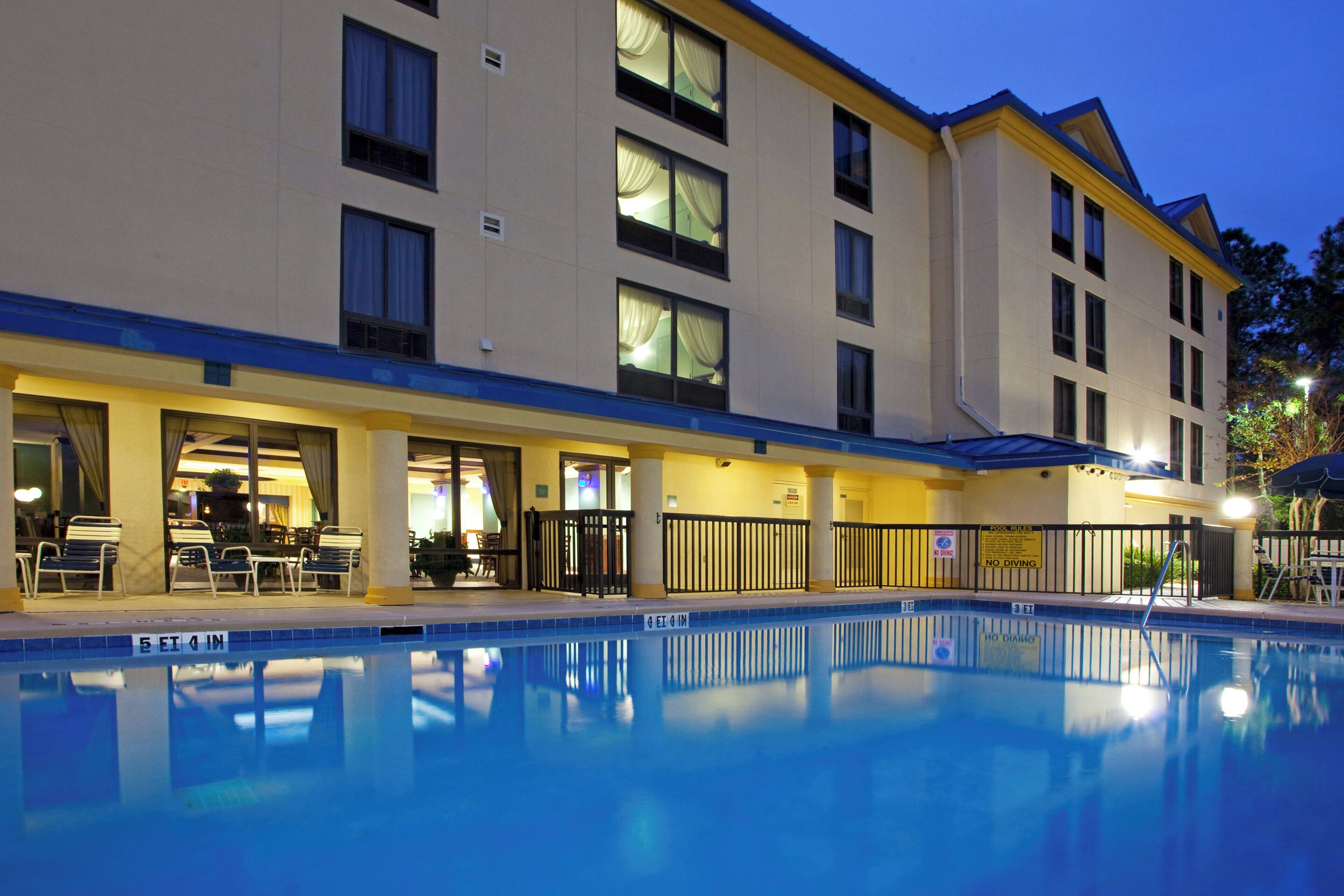 A hotel with a swimming pool, outdoor seating, and a covered area.