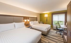 Quarto de hotel com duas camas, uma escrivaninha, uma cadeira e janela com vista para o verde.
