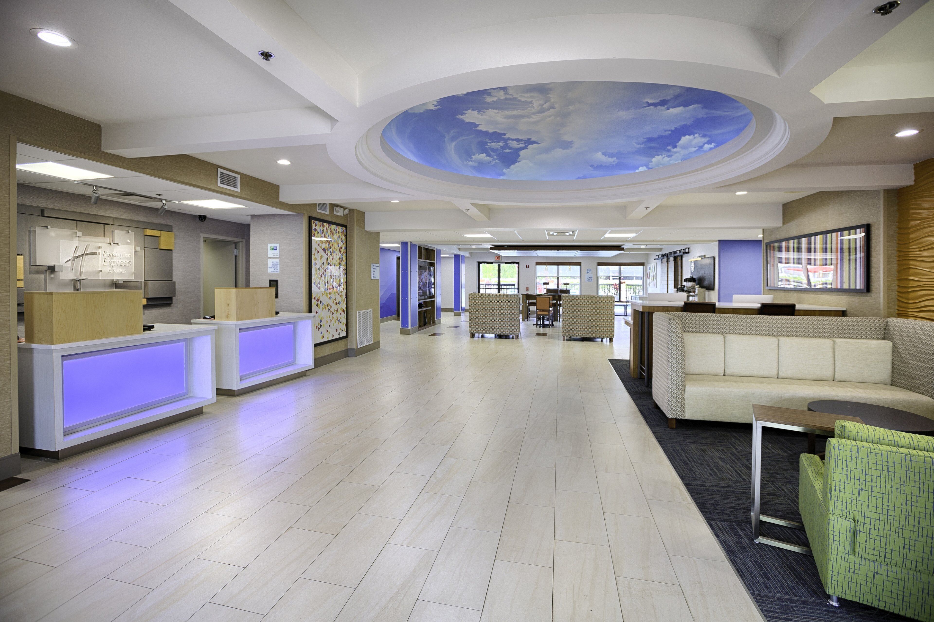 Een receptiegebied van een hotel met een modern design, met een receptiebalie, een zithoek en een plafondschildering.