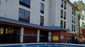 A modern building with a pool area, including a diving board and safety signs. - Holiday Inn Express Hotel & Suites Jacksonville - South by IHG (Jacksonville)