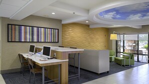 A modern reception area with a reception desk, computers, seating, and a ceiling mural. - Holiday Inn Express Hotel & Suites Jacksonville - South by IHG (Jacksonville)