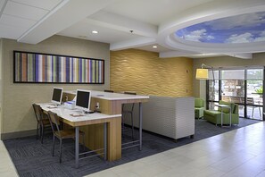 Una moderna zona de recepción con mostrador, computadoras, asientos y un mural en el techo.