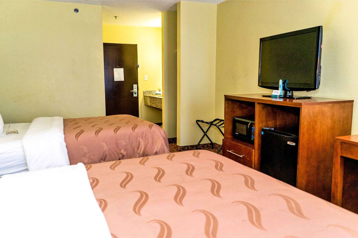 Une chambre d’hôtel avec deux lits, une télévision, un four à micro-ondes et un réfrigérateur.