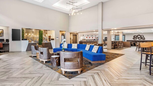 A spacious lobby with a blue sectional sofa, leather armchairs, and a herringbone-patterned floor. - Best Western Plus Bourbonnais Hotel & Suites (Bourbonnais)