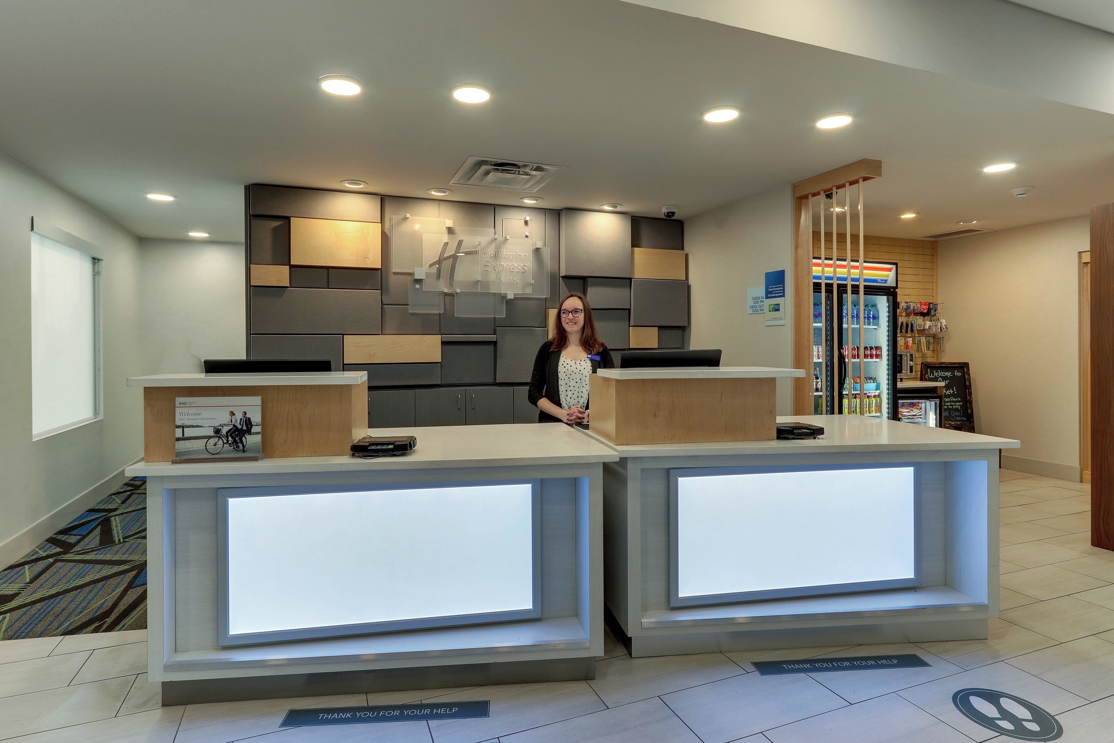 A reception desk with a digital display, a Holiday Inn Express sign, and a 7-Eleven convenience store in the background.