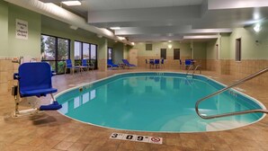 Une piscine intérieure avec des chaises bleues, un panneau indiquant la présence d’un sauveteur et un autre panneau indiquant l’absence de sauveteur.
