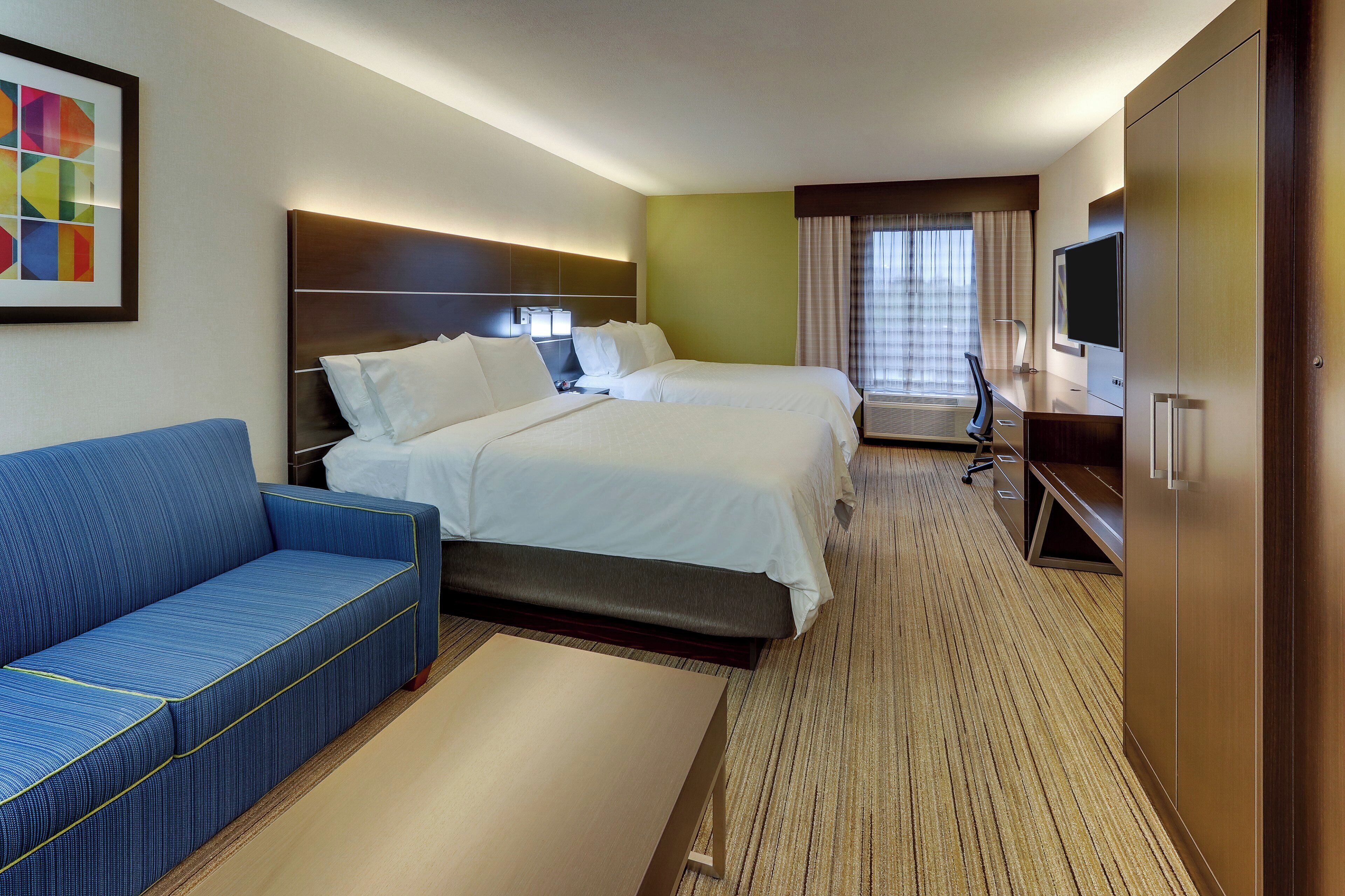 A hotel room with a bed, a sofa, a TV, and a desk.