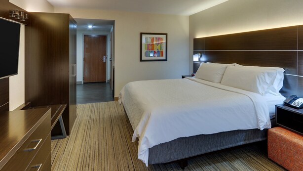 Une chambre d’hôtel dotée d’un grand lit, d’un téléviseur à écran plat, d’un bureau et d’une tête de lit moderne.