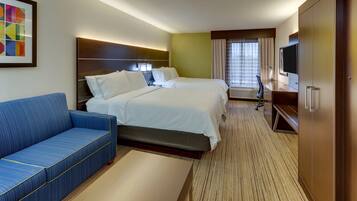 A hotel room with two beds, a sofa, a TV, and a desk.