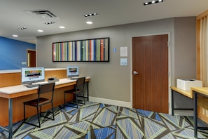 Ein Hotel-Empfangsbereich mit zwei Computerarbeitsplätzen, einem großen, gestreiften Kunstwerk an der Wand und einem Schild für die Gepäckaufbewahrung.