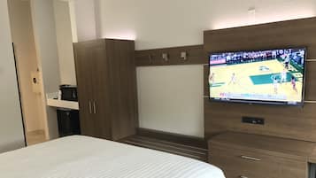 Camera d'albergo con un letto, una TV a muro, un armadio e una piccola scrivania con macchina per il caffè.