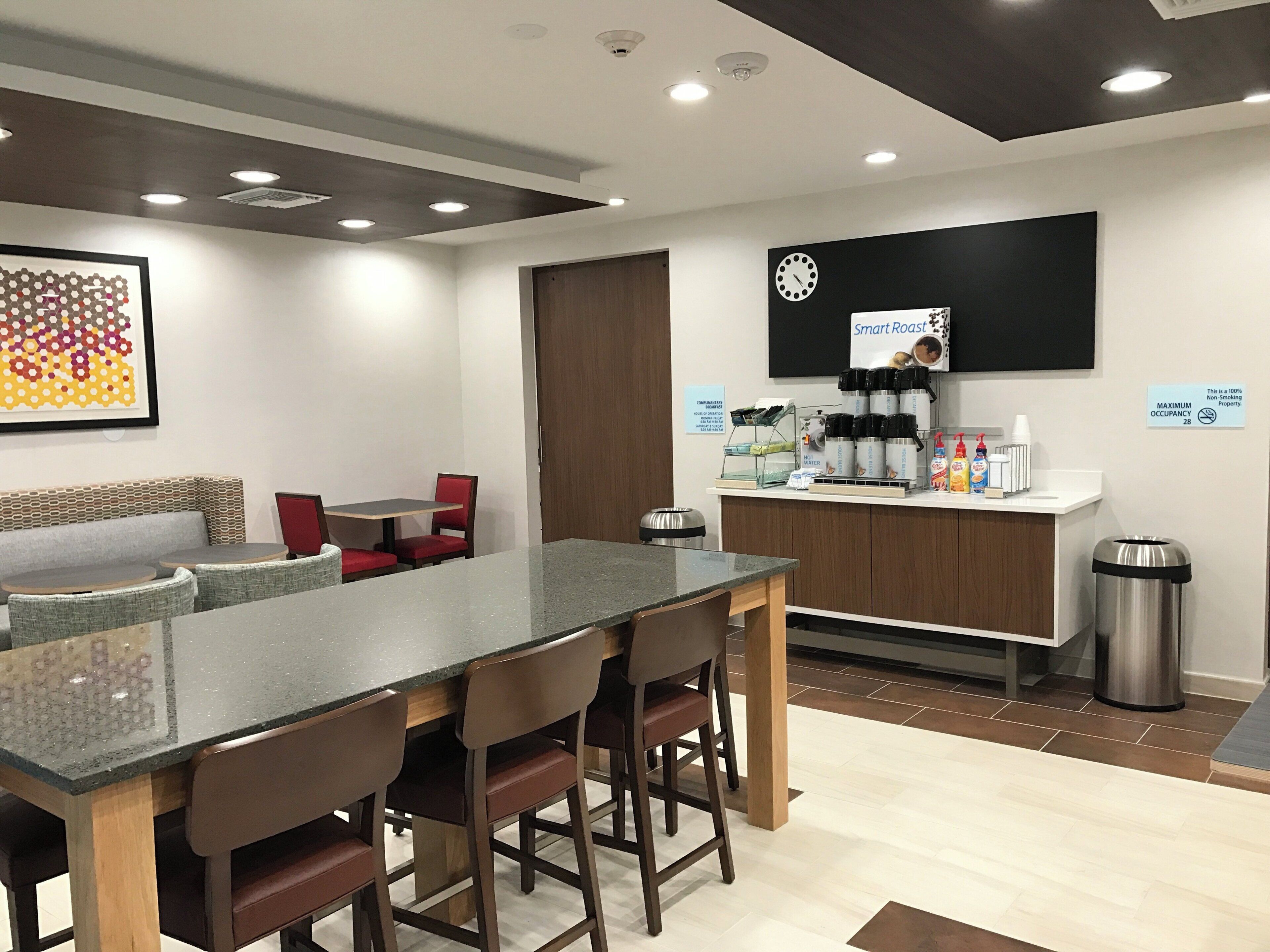 Un área de cocina moderna con barra, asientos y estación de café.
