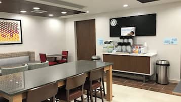 Un área de cocina moderna con barra, asientos y estación de café.