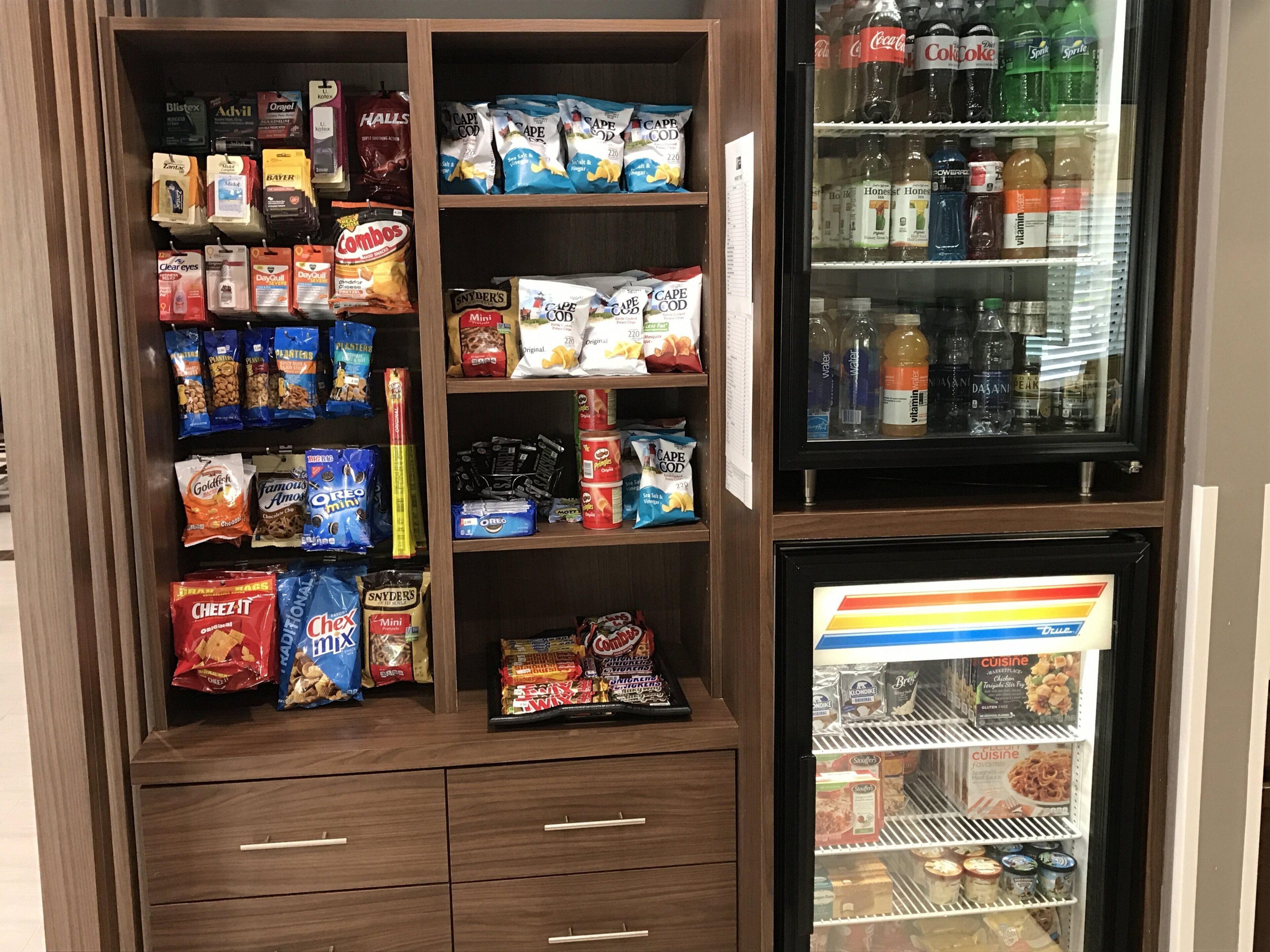 A snack and beverage display with various brands and types of snacks, including chips and crackers, and a refrigerated section with beverages and ice cream.