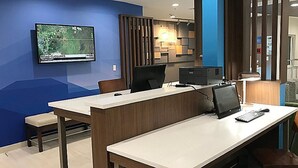 A modern office space with a desk, computer, and a television displaying road closures. - Holiday Inn Express Naples South I-75 by IHG (Naples)