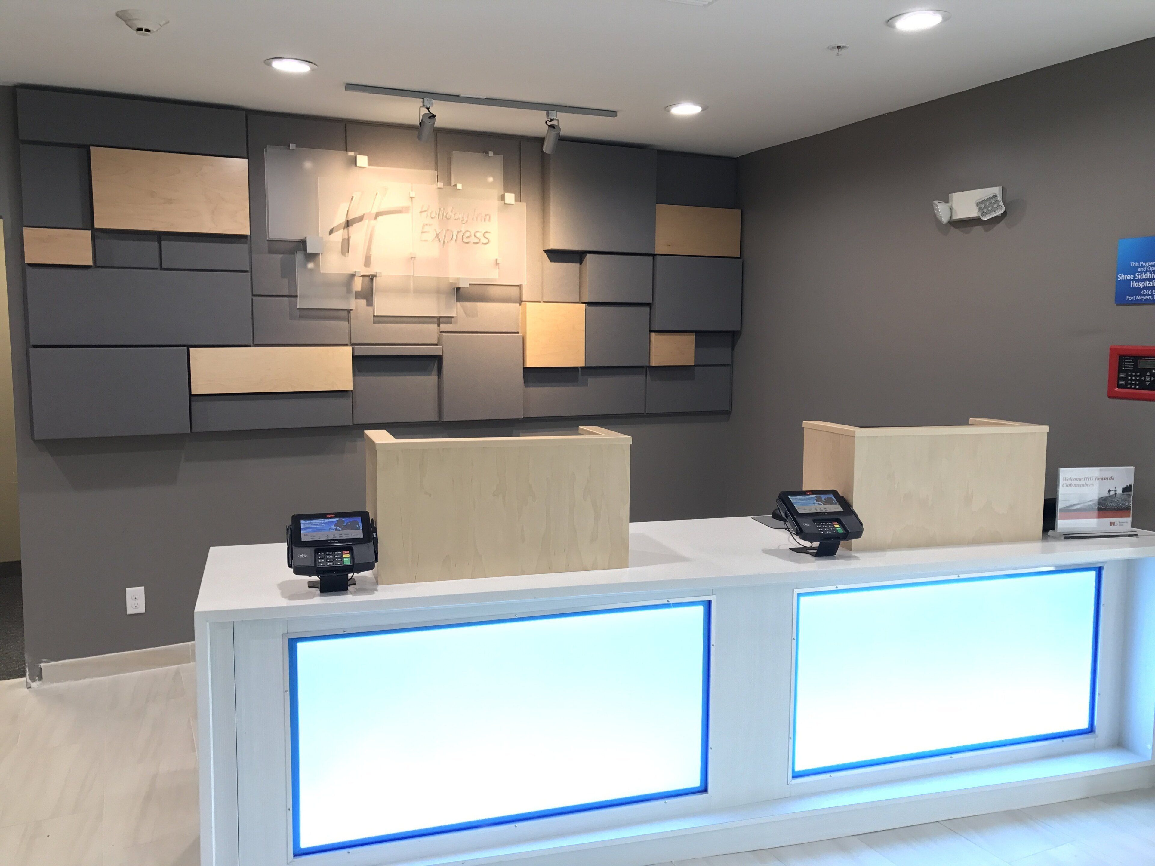 Una recepción de hotel con diseño moderno, que incluye una pantalla digital y un terminal de pago.