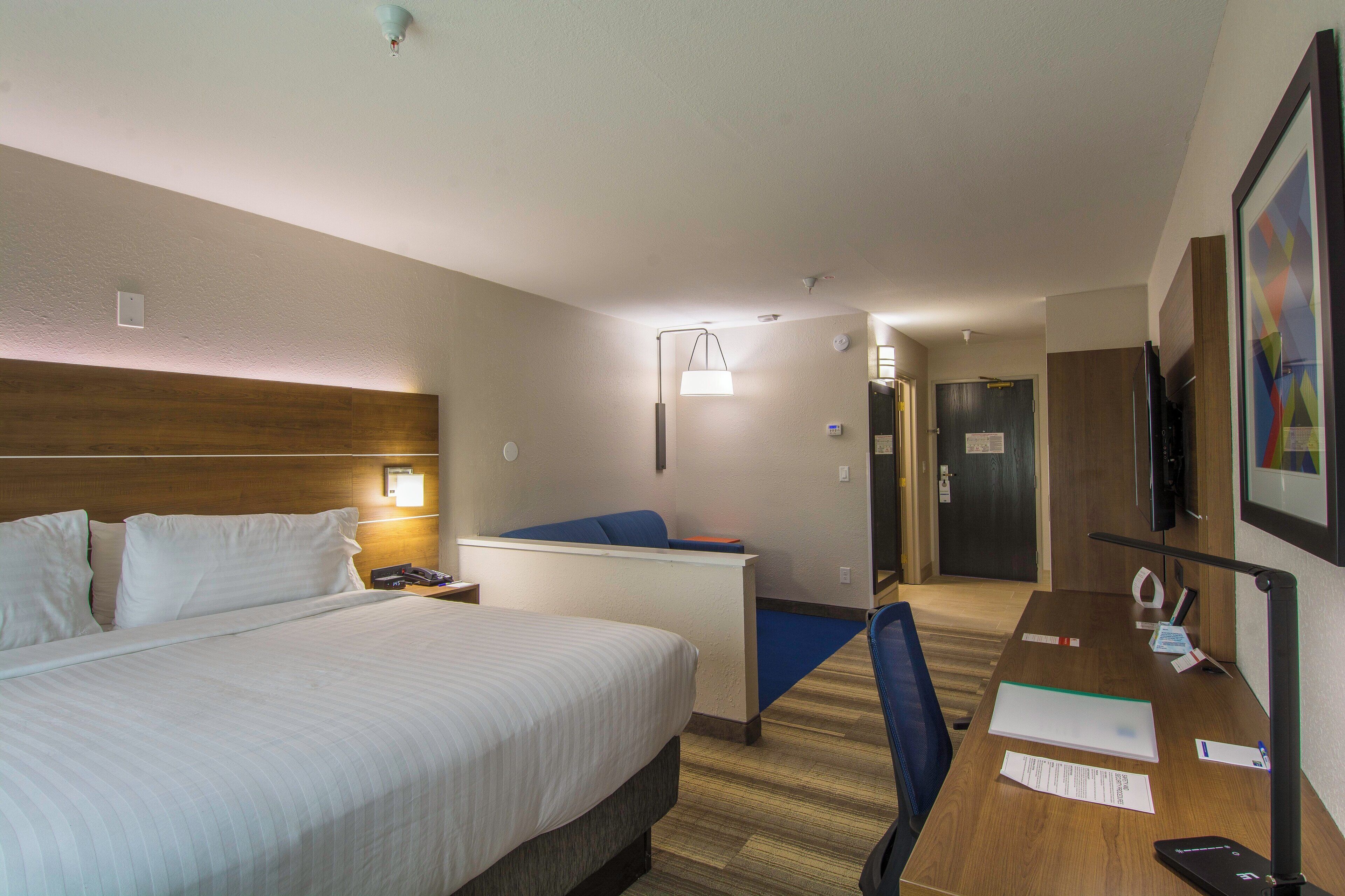Una habitación de hotel con cama, escritorio, silla y televisión.