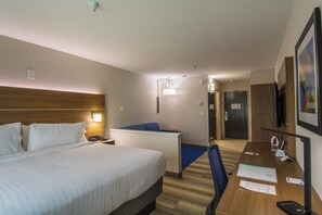 Una habitación de hotel con cama, escritorio, silla y televisión.