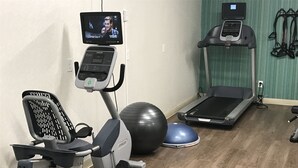 A home gym with an elliptical, a stationary bike, a treadmill, a large exercise ball, and a blue mat. - Holiday Inn Express Naples South I-75 by IHG (Naples)
