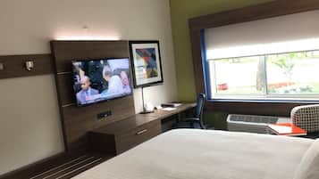 Une chambre d’hôtel comprenant un lit, un bureau avec une chaise, un téléviseur fixé au mur et une fenêtre donnant sur l’extérieur.