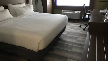Une chambre d’hôtel avec un grand lit, un bureau et une fenêtre avec des stores.